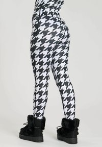 Black and white houndstooth leggings, fitted design, stretchy material, high waist. Paired with fluffy black ankle boots.