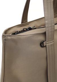 Coin de sac en toile beige avec de solides poignées, fermeture éclair noire avec tirette en tissu et détail en anneau noir sur le côté.