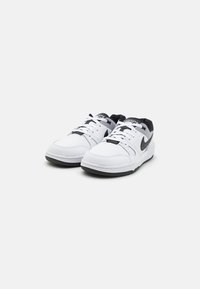 Baskets basses en matériau synthétique blanc avec des accents noirs. Elles présentent une doublure grise, des lacets plats et une semelle en caoutchouc texturé.