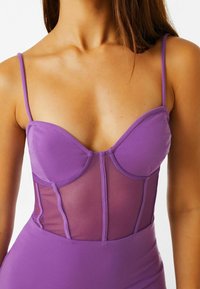 Body viola con pannello in rete e coppe strutturate. Spalline sottili e texture liscia creano una silhouette aderente con un design moderno.