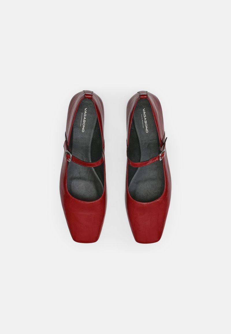 Röda läderskor med fyrkantig tådesign, ankelrem och kontrasterande svart innersula. Slät, glänsande yta med ett spänne som accent.