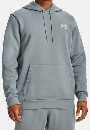 Mann trägt eine hellgraue Under Armour Kapuzenjacke mit Fronttasche und Kordelzug, kombiniert mit passenden Jogginghosen.