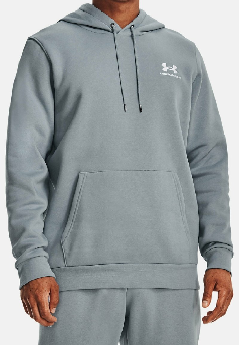 Homme portant un sweat à capuche Under Armour gris clair avec poche avant et cordons, associé à un pantalon de survêtement assorti.