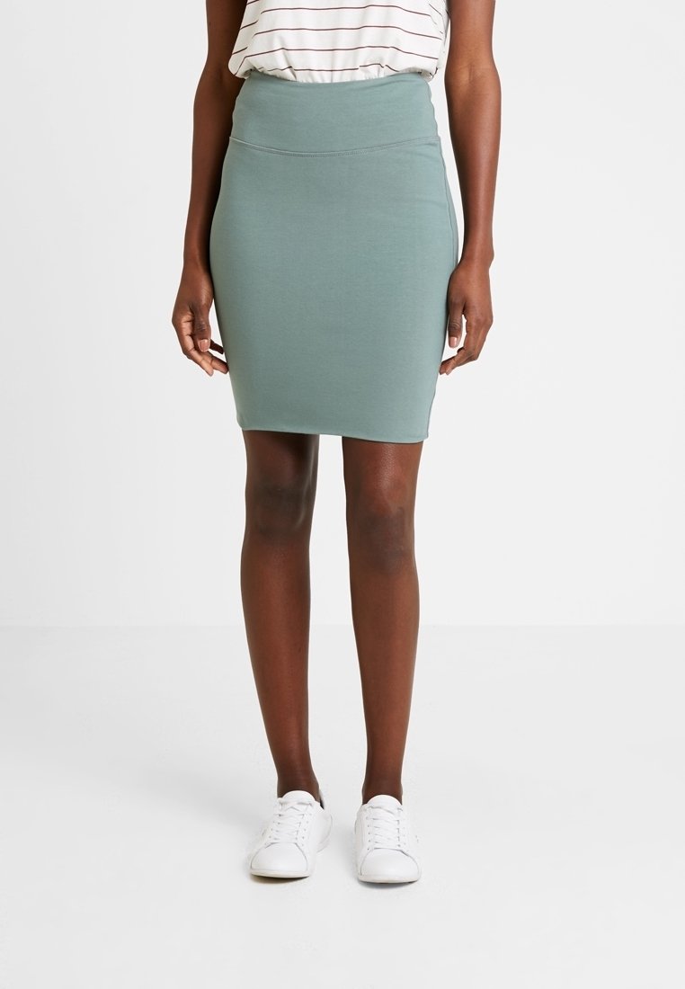 Jupe crayon vert menthe en matière extensible. Design taille haute avec une texture lisse, assortie à des baskets blanches.