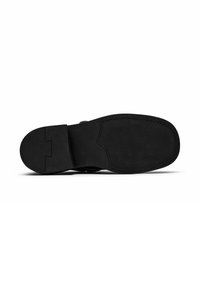 Sole di scarpa in pelle nera con superficie in gomma texturizzata, con una sezione liscia e cuciture a contrasto lungo il bordo.