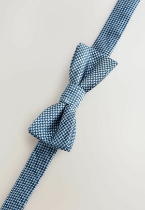 Sininen ruudullinen kangastepuksolmio, jossa on tekstuuri; siinä on näkyvä rusetti ja yksivärinen hihna kaulaan pujottamista varten.