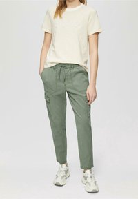Béžové pruhované tričko s nápisem "shine", v kombinaci se zelenými cargo kalhotami se bočními kapsami, stahovacími pasem a manžetami na nohavicích.