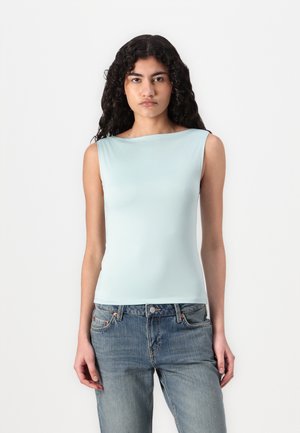 Top sin mangas de color azul claro en tejido suave, con escote barco y silueta ajustada, combinado con vaqueros azul desgastado.