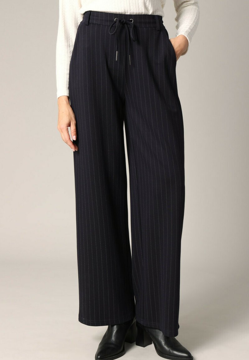 Marinekleurige pantalon met wijde benen en verticale witte streepjes, gemaakt van een gladde stof. Beschikt over een elastische tailleband metkoord en zijzakken.