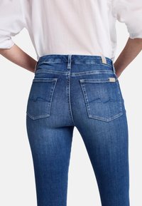 Högmidjade blå denimjeans med en jämn struktur, som har två bakfickor och kontrasterande sömnad på de kurviga fickdesignerna.