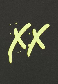 Crna tkanina s odvažnim, neon žutim dizajnom "XX" s efektom prskanja. Otisak ima strukturalni izgled nasuprot glatkoj pozadini.