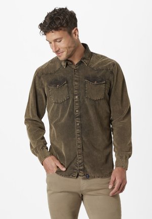 Green corduroy shirt with button-down front, two chest pockets, and stitched detailing. Long sleeves with button cuffs, textured fabric.