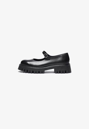 Scarpa nera in stile Mary Jane in pelle con punta rotonda, cinturino alla caviglia e suola in gomma spessa con dettagli rigati.