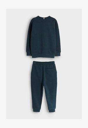 Marineblauwe sweatshirt en joggingbroek set. De sweatshirt heeft ribgebreide boorden; de broek heeft een elastische tailleband en een achterzak. Zachte stoftextuur.