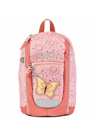 Pink backpack with a rounded design and donut pattern. Features a butterfly patch, reflective accents, and a textured zipper pull.
