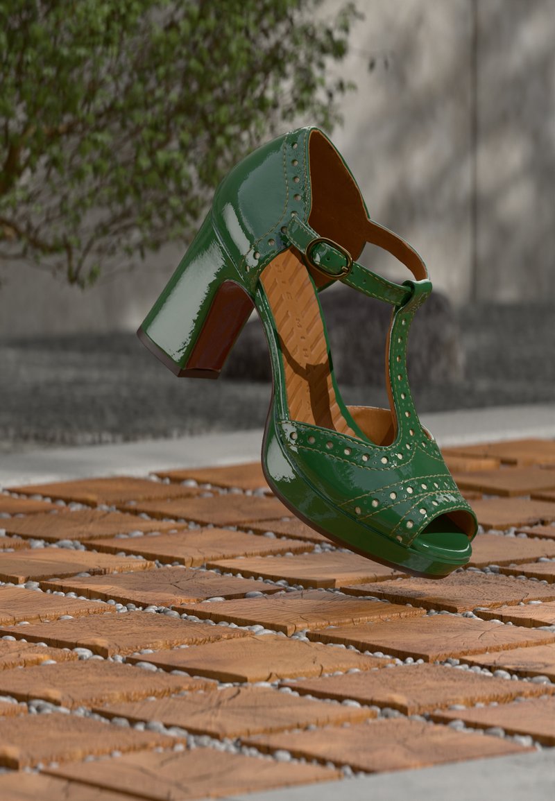 Chaussure à talon haut en cuir verni vert, à bout ouvert, avec bride à la cheville et détails décoratifs à clous ; un talon bloc soutient un design robuste.