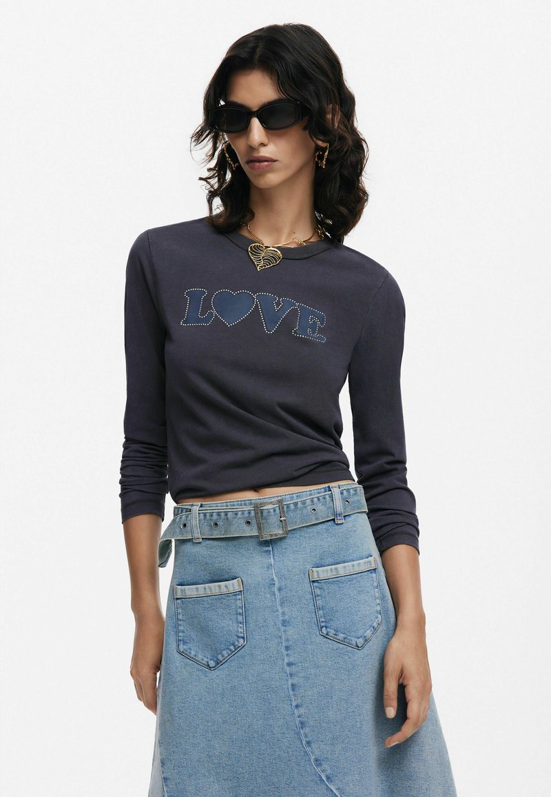 Maglia a maniche lunghe blu navy con design metallico "LOVE", abbinata a una gonna in denim azzurro chiaro con cintura e tasche angolari.