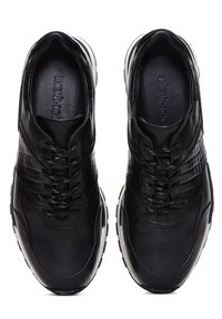 Chaussures de sport noires avec une tige synthétique texturée, un système de laçage et des semelles blanches contrastantes. Bout arrondi et design respirant.