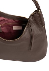 Borsa a tracolla in pelle marrone con superficie texturizzata, zip dorata e interno in tessuto bordeaux, con etichetta del marchio "Coccinelle."