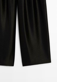 Zwarte brede broekspijpen gemaakt van zijdeachtig materiaal; gladde textuur, ontwerp tot op de vloer, met subtiele glans en minimale details.