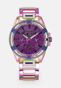 Montre Purple Guess avec un boîtier métallique multicolore, des accents en cristaux sertis autour de la lunette et un bracelet métallique à maillons.