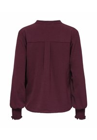 Blouse à manches longues de couleur violet foncé avec poignets froncés et empiècement dos avec un pli creux central inversé.