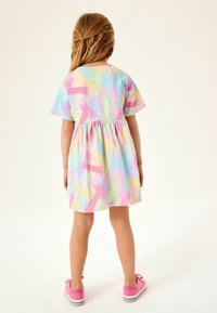 Lyhythihainen mekko pastelliväreissä, jossa on abstrakteja siveltimenvetoja. Elastinen vyötärö, pehmeä materiaali, ulottuu polven ylle. Yhdistetty vaaleanpunaisiin kenkiin.