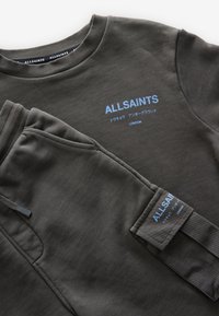 Grå sweatshirt och byxset i mjukt tyg. Har ribbade muddar, ljusblå logodetaljer och en avslappnad passform.