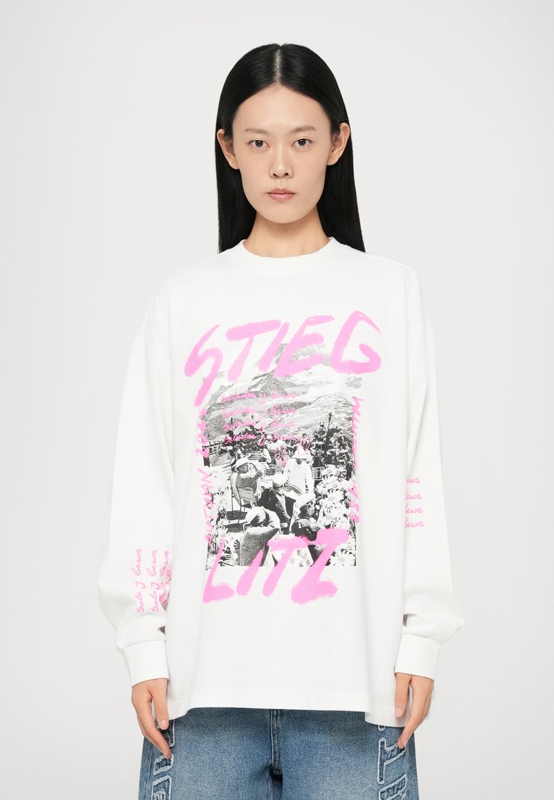 White long-sleeve sweatshirt featuring a central black and white photo, surrounded by pink text and graphic elements. Relaxed fit and soft texture.