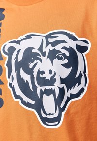 Orange bomullströja med en stor björngrafik i mörkblått och vitt, som visar tydliga ansiktsdrag och en öppen mun.