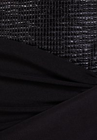 Svart texturerad tyg med ett glansigt rutmönster lagrat över mjukt, matt svart tyg, som visar upp kontrasterande material och ytor.