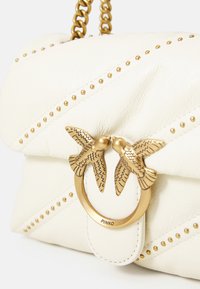 Sac à main en cuir blanc avec des coutures diagonales et des clous dorés. Doté d'un fermoir en forme d'anneau doré orné de deux accents en forme d'oiseaux. Chaîne fournie.