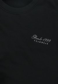 Czarny sweatshirt z okrągłym dekoltem, wykonany z gładkiego materiału, z białym haftowanym napisem "Prosto 1999 TEAMWEAR" umieszczonym po lewej stronie.