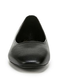 Ballerines noires en simili cuir avec un bout rond et une texture lisse, présentant un profile bas et sans embellissements ni accessoires visibles.