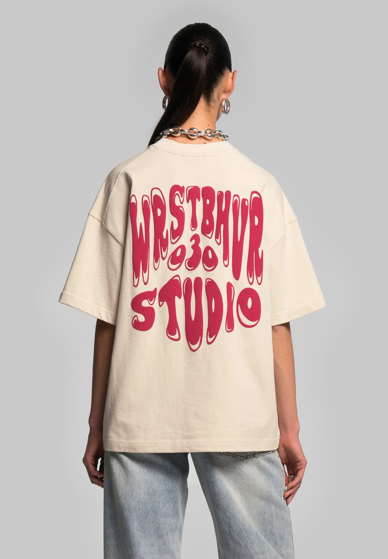 Krémové, oversize tričko s krátkými rukávy, na zadní straně s velkým růžovým psychedelickým textem "WRSTBHVR 030 STUDIO".