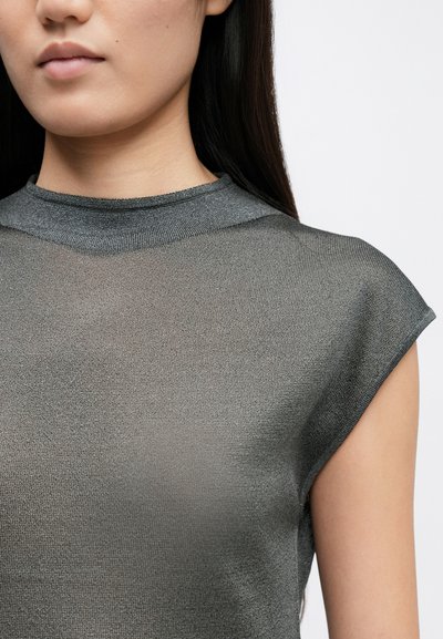 Szürke, áttetsző blúz magas nyakkivágással és kis ujjakkal. Az anyag textúrált szövése finoman tükrözi a fényt.