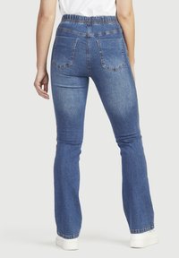 Uppblåsta blå denimjeans med elastisk midja, med två bakfickor och en blekt tvätt. Slät textur med en lätt stretch.