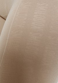 Beige leggings med tekstureret design med subtile mønstre. Lavet af strækbart materiale, der viser en glat finish og tætsiddende form.