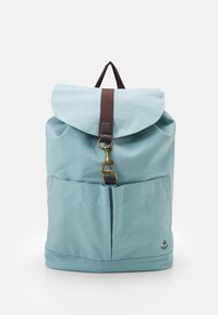 Helleblaue Stoff-Rucksack mit braunem Riemen, Messingverschluss, zwei Vordertaschen und kleinem Ankerlogo in der unteren rechten Ecke.