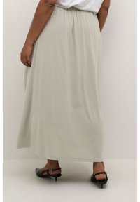Light gray maxi skirt with a smooth texture, elastic waistband, and flowing design. Paired with black heeled sandals.