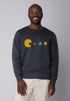 Dark navy sweatshirt featuring a large yellow Pac-Man graphic and four colorful, cartoonish eyes with varying expressions.