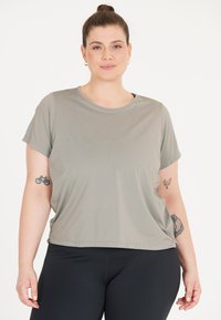 Grå t-shirt med kort ärm i mjukt tyg, med rund ringning och avslappnad passform, kombinerat med svarta leggings.