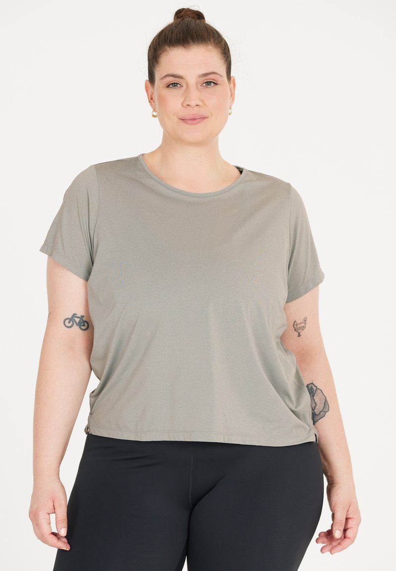 Grå t-shirt med kort ärm i mjukt tyg, med rund ringning och avslappnad passform, kombinerat med svarta leggings.
