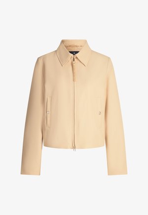 Veste beige courte avec col pointu, fermeture éclair à l'avant et deux poches à rabat. Présente un tissu lisse et texturé ainsi qu'un détail de couture subtil.