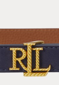 Navy oda diržo, turinčio auksinį, virvės tekstūros "RL" logotipo sagtį. Lygus paviršius su kontrastinga rudą vidinę pamušalą.