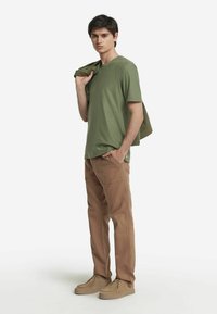 Olivgrön kortärmad t-shirt, i par med ljusbruna cargobyxor. Enkl design med avslappnad passform. Bruna skor med snören för avslappnat bruk.