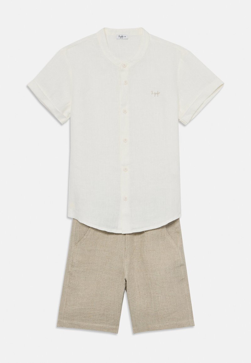 Lniana koszula z krótkim rękawem w kolorze ecru z zaokrąglonym kołnierzykiem i guzikami, zestawiona z beżowymi szortami o fakturze, posiadającymi boczne kieszenie.