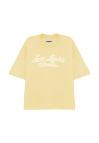 T-shirt en coton jaune à manches courtes, avec le texte "Low Lights Studios" en lettres cursives blanches sur le devant.