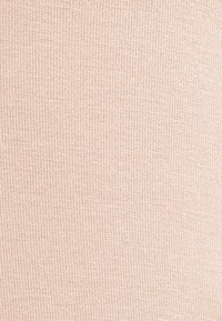 Tecido de malha rosa claro com uma textura suave, apresentando um design canelado que adiciona uma dimensão sutil e interesse visual.