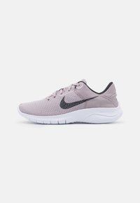 Baskets de course Nike rose clair avec une tige en maille, des accents noirs et une semelle flexible blanche. Comprend un design à lacets et une surface texturée.